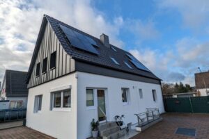 Satteldach mit sauber verlegten Solarpaneelen unter blauem Himmel.