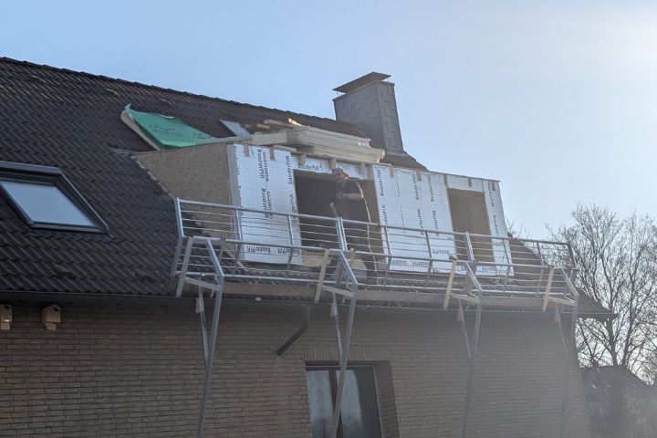 Handwerker beim Einsetzen eines neuen Dachfensters während der Dachsanierung.